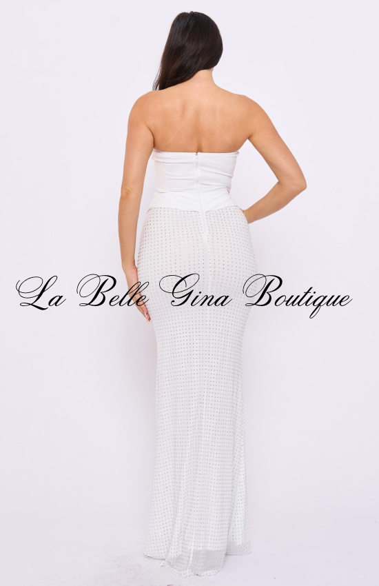 A woman models a floor-length white mermaid gown with a strapless sweetheart neckline and a structured corset-inspired bodice. The fitted design accentuates the waist and curves, while rhinestone embellishments throughout the skirt provide subtle sparkle. The elegant white color gives the dress a sophisticated and luxurious appearance, making it ideal for bridal events, formal occasions, and upscale celebrations.